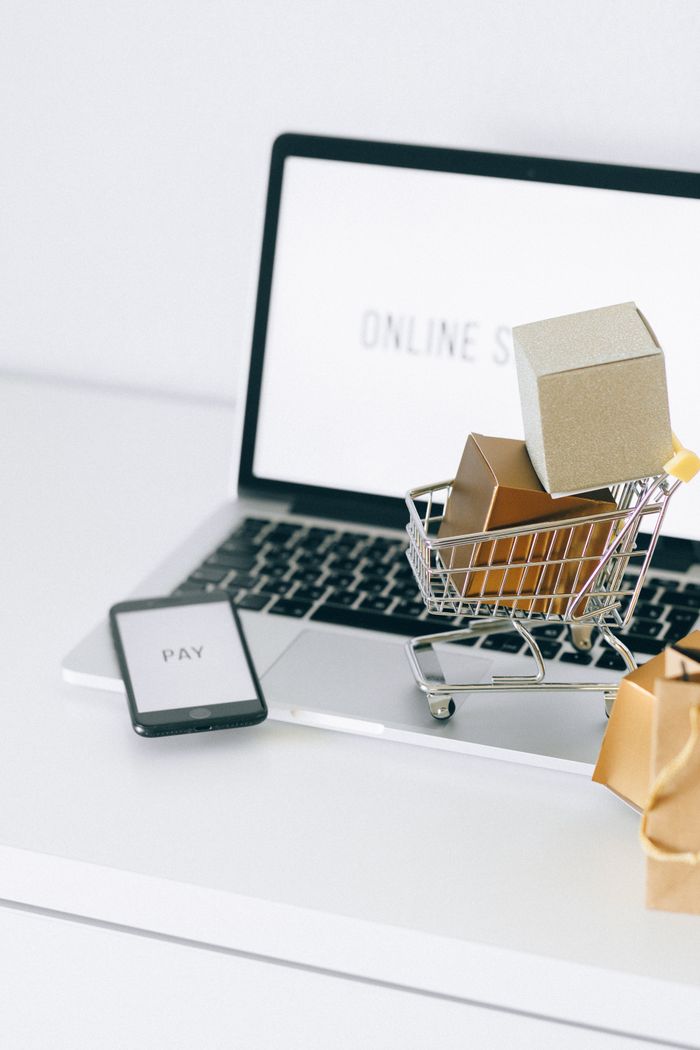 hero-img-01 Mini shopping cart on laptop symbolizing online shopping and e-commerce transactions.